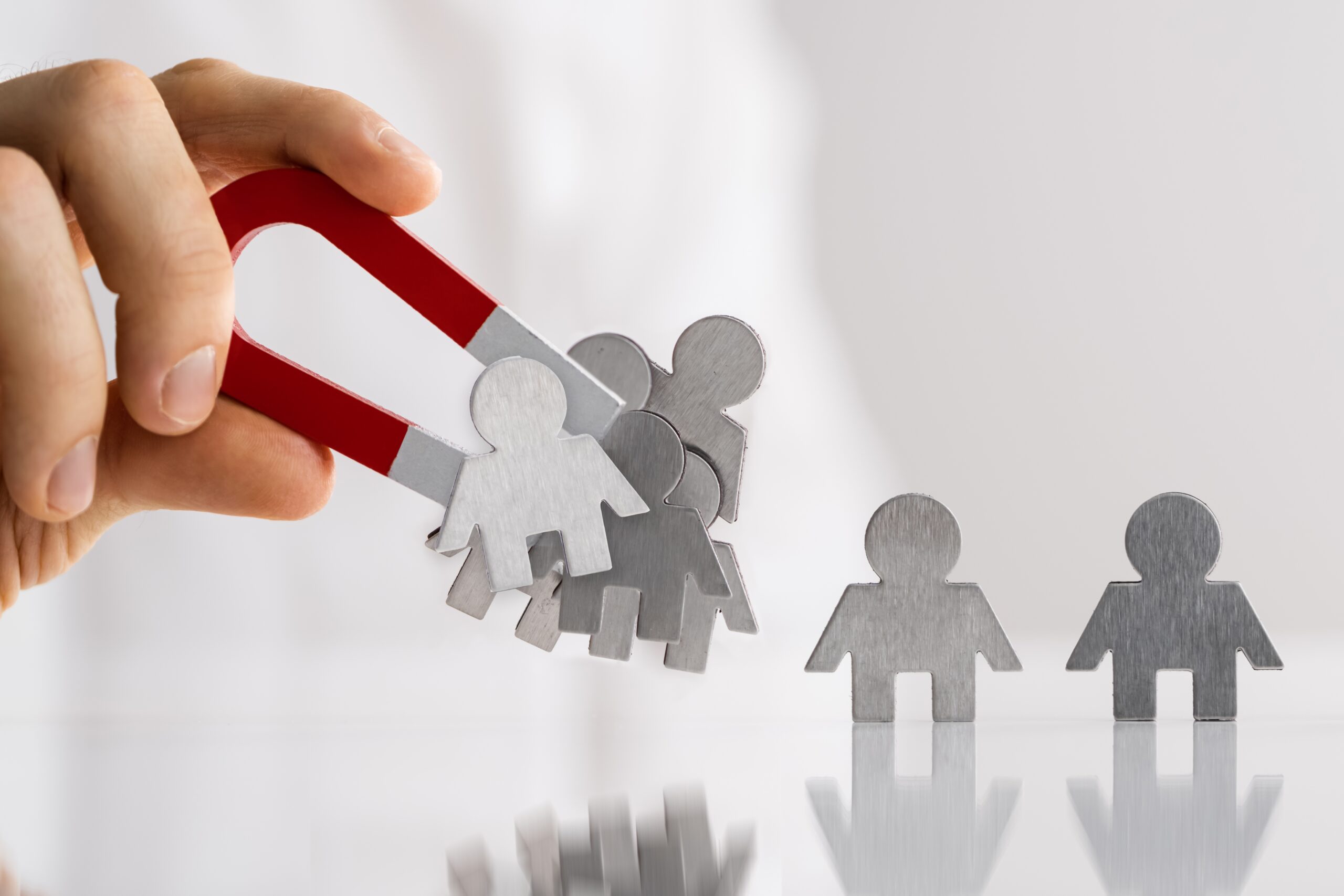 A hand holding a magnet attracting customers.